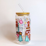 Szklany kubek 550 ml z bambusową pokrywką i słomką - pierniczki w różowych czapeczkach i szaliczkach wokół pastelowych kubków na wynos - pocichutku.pl