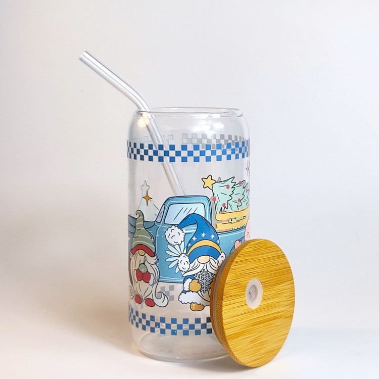 Szklany kubek 550 ml z bambusową pokrywką i szklaną słomką - skrzaty, a za nimi samochód z choinką na tylnej pace, całość zachowana głównie w pastelowym błękitnym kolorze - pocichutku.pl