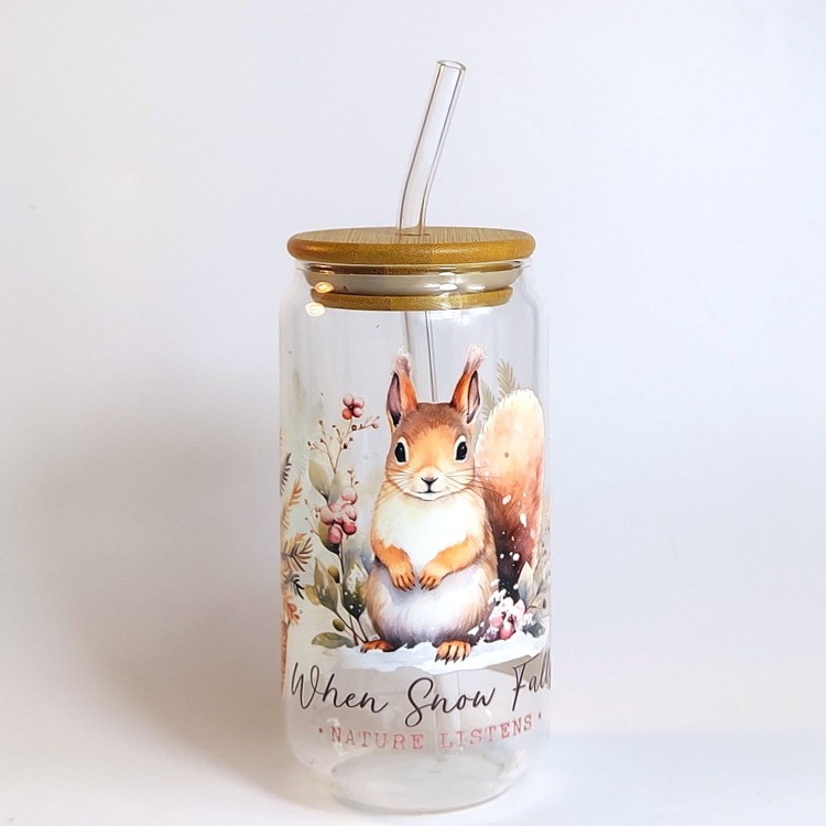 Szklany kubek 550 ml z bambusową pokrywką i szklaną słomką - wiewiórka siedząca na śniegu, a wokół niej dwie choinki w wiklinowych doniczkach - pocichutku.pl