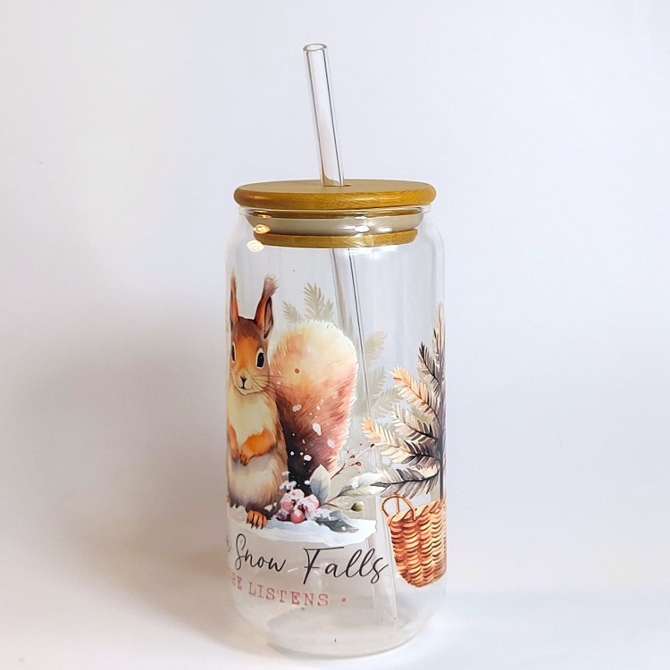 Szklany kubek 550 ml z bambusową pokrywką i szklaną słomką - wiewiórka siedząca na śniegu, a wokół niej dwie choinki w wiklinowych doniczkach - pocichutku.pl