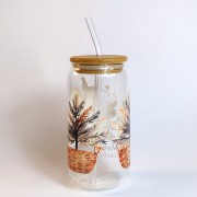 Szklany kubek 550 ml z bambusową pokrywką i szklaną słomką - wiewiórka siedząca na śniegu, a wokół niej dwie choinki w wiklinowych doniczkach - pocichutku.pl